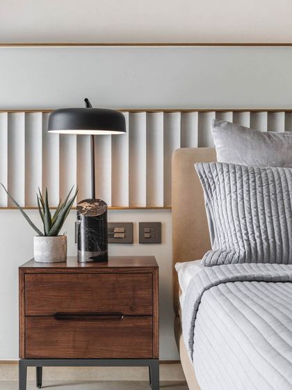 In this guest room, the headboard was creatively designed using remnants from paneling used elsewhere in the home, promoting waste reduction and design continuity. The fluted panel is framed in brass for a touch of elegance.