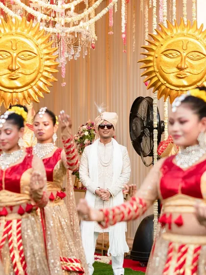 A close-up of the groom's royal entry, framed by his dancing entourage. The focus on the groom's confident stance amidst the motion and props emphasizes the personal yet grand nature of the celebration.