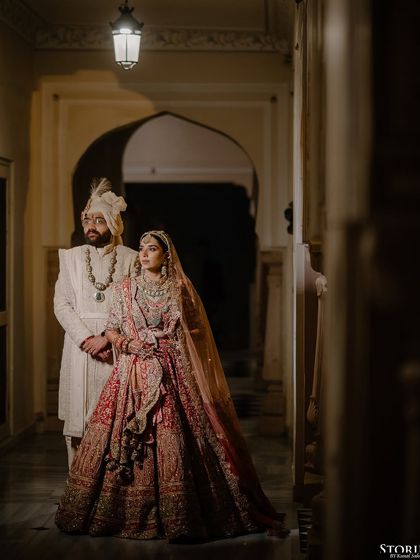A regal portrait of Rahul and Aashi in a palace corridor, the lighting creating a dramatic and timeless feel.