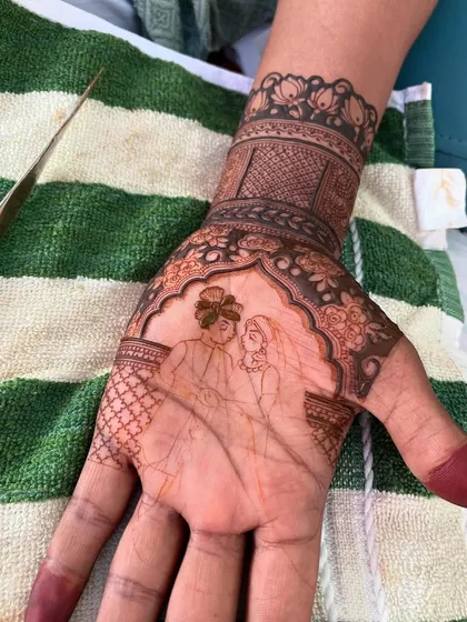 The process of creating a couple's portrait begins with a delicate outline. This image shows the initial sketch on the palm before the details and shading are filled in.