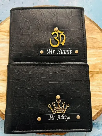 Two black croc wallets showing different charm options. One features a spiritual 'Om' symbol and the other a classic crown.