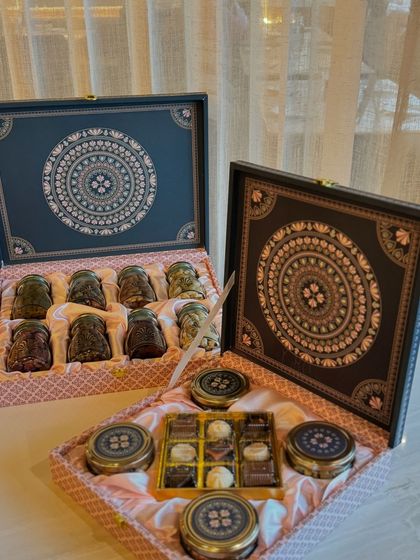 A matching set of two intricately designed gift boxes. One contains an assortment of our signature modak-shaped chocolates, while the other holds a variety of truffles and dry fruit tins, perfect for festive sharing.