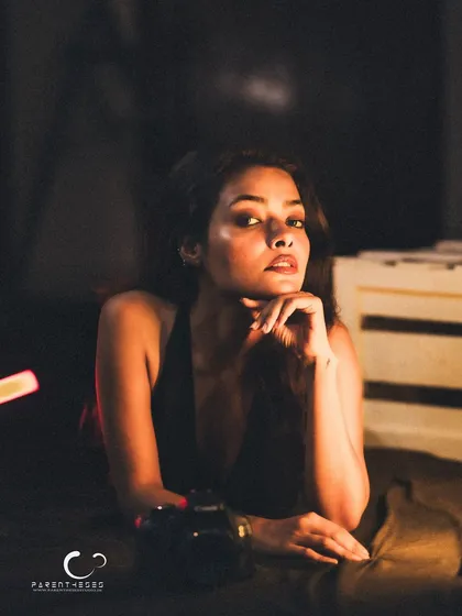 A confident and poised portrait. The camera prop adds a layer to her character, suggesting she is both the subject and the storyteller.