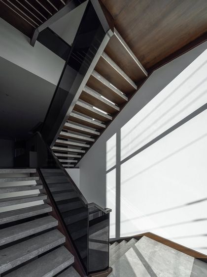 The staircase in the Silhouette home is a study in light and shadow. The simple, clean lines of the steps and the glass railing allow sunlight to pass through, creating shifting patterns on the wall throughout the day.