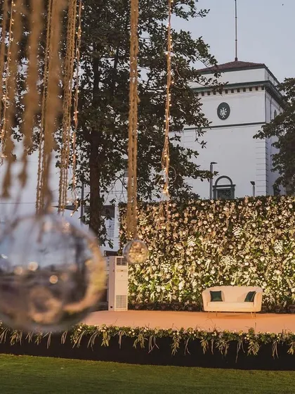 A simple yet sophisticated stage setup with a full floral wall and hanging disco balls. This design proves that even minimalist concepts can have a powerful impact, especially against a scenic backdrop.