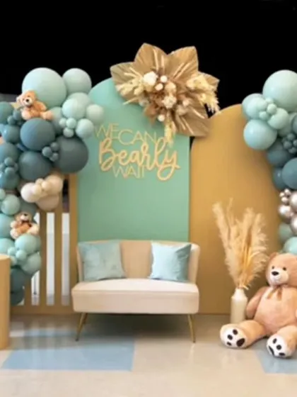 A unique take on the "We Can Bearly Wait" theme with a beautiful teal, beige, and silver color scheme. This setup includes a comfortable loveseat for guests, multiple teddy bears nestled in the balloons, and elegant pampas grass details.