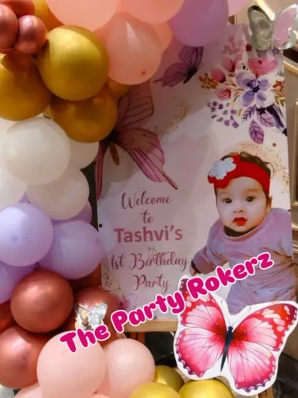 A close-up of the personalized welcome easel for a first birthday party. The baby's photo and the butterfly theme make it a sweet and personal touch.