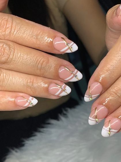 A close-up of this intricate design, showing the delicate gold lines and rhinestone details over a classic French manicure.