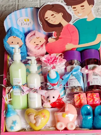 A large and luxurious baby shower hamper in a decorated pinewood tray, filled with soaps, candles, lotions, and even mouth fresheners.