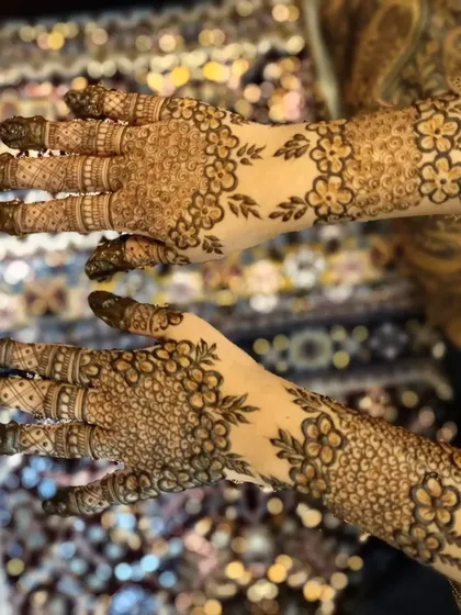 A very fine and detailed floral pattern, known as a "jaal" or net design. The tiny flowers create a beautiful, textured look across the back of the hands.