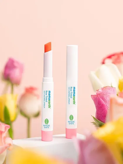 This shot uses a soft-focus floral foreground to create a dreamy, romantic mood for a rose-tinted lip balm. The styling aims to evoke the delicate and beautiful feeling of the product itself.