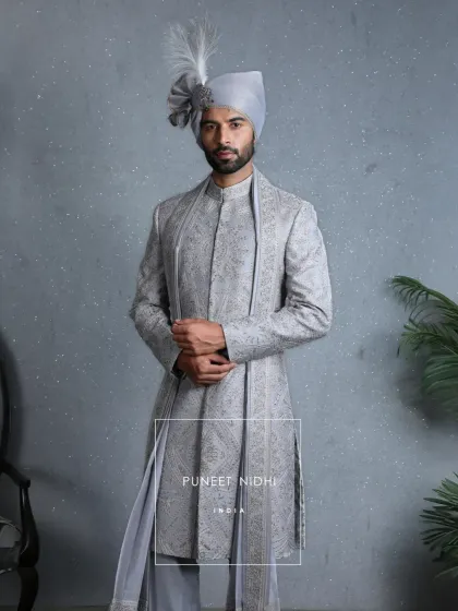 Inspired by Mughal grandeur, this powder blue sherwani is a vision of heritage. It is embroidered with intricate zari, handwoven florals, and sequins that sparkle like blessings, making it a living legacy carried forward with pride.