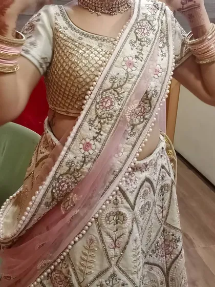 A client trying on the ivory lehenga, showing how the dupatta can be draped. The pearl border on the dupatta adds a touch of elegance to the overall look.