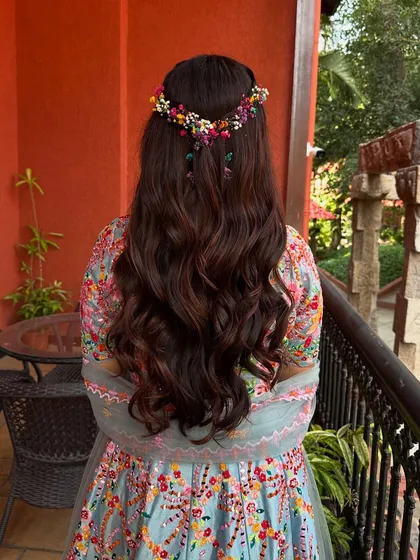 Another view of the beautiful floral hair crown on a bed of soft waves. The colors of the flowers perfectly match her vibrant lehenga.