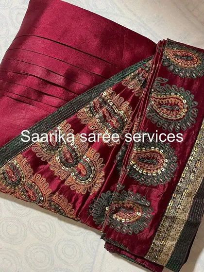 A deep red saree with a heavy embroidered velvet border.