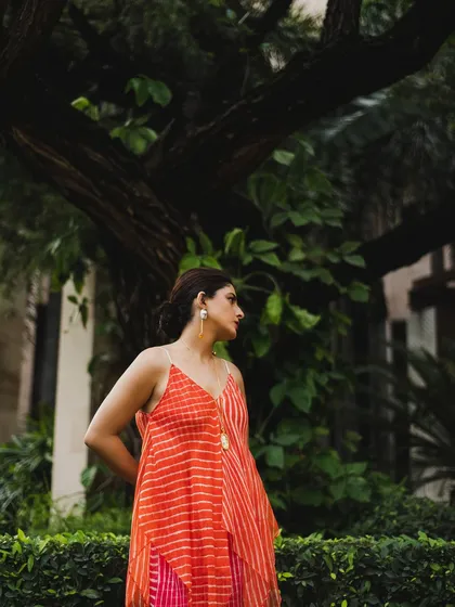Isha Talwar in a garden setting. The lush green background makes the warm colors of her dress pop, creating a vibrant and lively portrait.