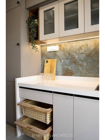 This modern classic kitchen combines light grey cabinets with a striking backsplash. We included practical details like open wicker baskets for vegetable storage, blending functionality with rustic charm.