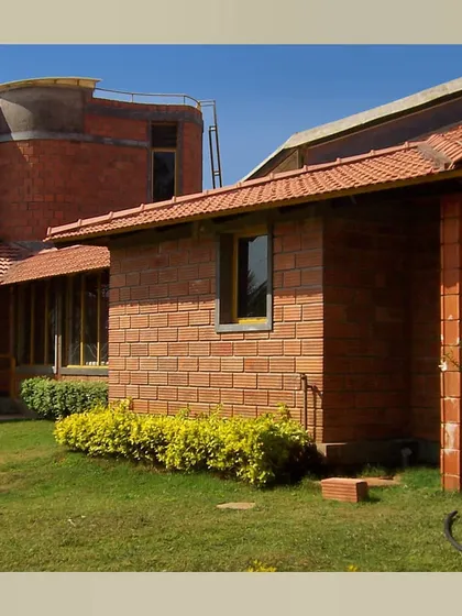 The farmhouse exterior, showing the hollow clay block walls, Mangalore tile roofs, and the central courtyard space.