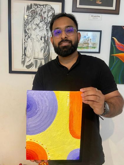 A participant proudly holds up his colorful abstract canvas painting. My workshops encourage you to experiment with color and shape.