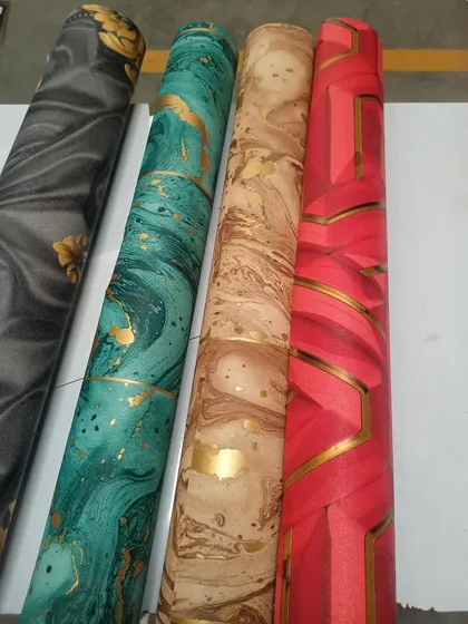A selection of four of our premium wallpaper rolls with golden leafing details. You can see the variety of colors and patterns, from marble swirls to geometric designs.
