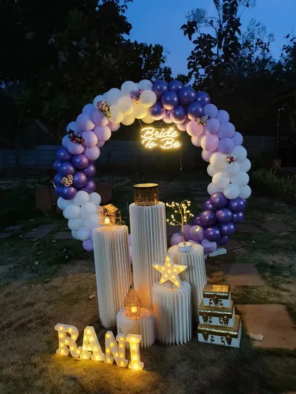 I can transform any outdoor space, even at night. This 'Bride to be' garden party setup uses a lighted balloon ring, a glowing neon sign, and illuminated marquee letters to create a dreamy and enchanting ambiance perfect for an evening celebration.