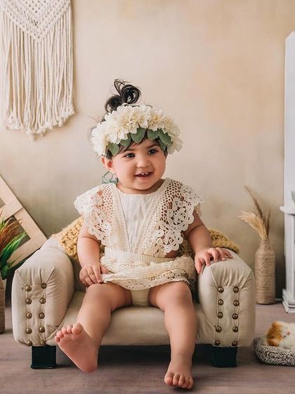 This little cutie in her lace romper is sitting happily in a mini armchair, part of a beautiful boho-chic milestone session.