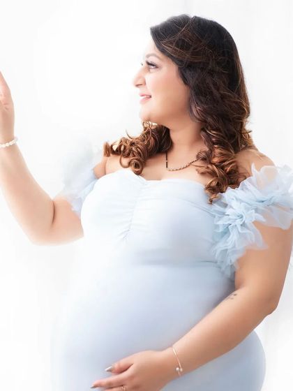 A candid, light-filled portrait. The mother-to-be waves gently, her smile genuine and bright. This image captures the happy, relaxed atmosphere I strive for in every session.