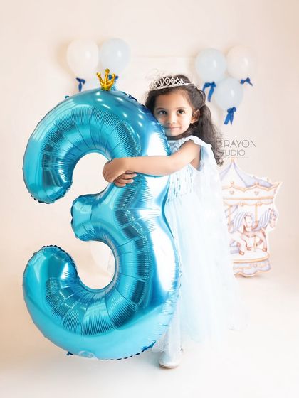 A big hug for a big number three balloon. This shot perfectly captures the scale and excitement of turning three.