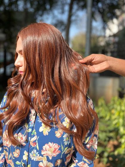 A stylist's hand showing the texture and health of the hair after the Copper Brown Melt service.