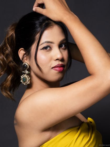 A close-up beauty shot, focusing on the model's earrings and makeup.