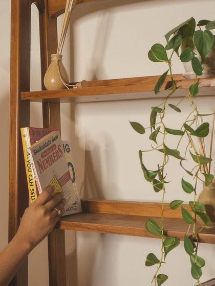 A closer look at the teak bookshelf, showing how it can be styled with books, plants, and diffusers. The warmth of the wood adds a touch of elegance to any space.