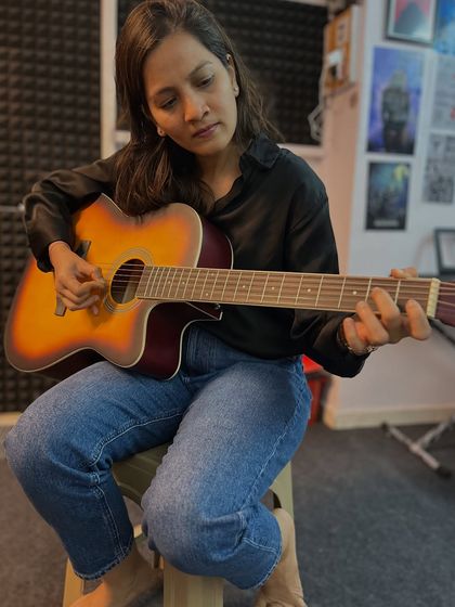 A student is focused during her guitar lesson. We provide a comfortable and encouraging environment for everyone, especially for women who want to learn an instrument.