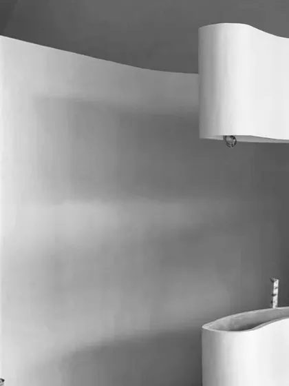 A detail shot in black and white, emphasizing the pure, sculptural forms of the curved walls and partitions within the space.