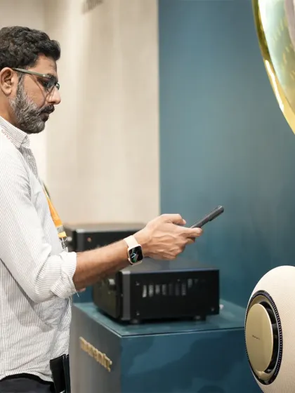 A visitor uses their phone to interact with a high-end smart speaker, demonstrating the seamless integration between personal devices and home audio systems.