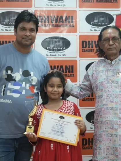 A student, her father, and our senior guru pose with her trophy.
