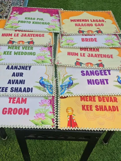 A collection of fun and quirky photo props for guests. These signs feature popular Hindi wedding phrases like 'Dulhan Hum Le Jaayenge' and 'Mehendi Lagao, Naacho Gao', adding an interactive element to the celebration.