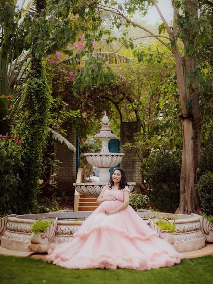 A serene portrait of an expecting mother by the garden fountain, a classic and elegant shot.