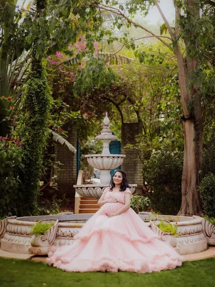 A serene portrait of an expecting mother by the garden fountain, a classic and elegant shot.