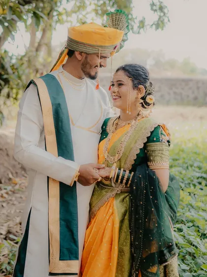 A lovely portrait of the couple holding hands and sharing a sweet, knowing look. Their coordinated traditional outfits look stunning against the natural backdrop.