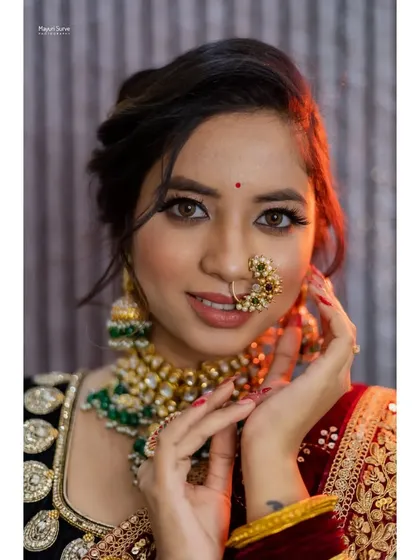 A close-up portrait from a bridal shoot, focusing on the intricate makeup, the traditional nath (nose ring), and the model's expressive eyes.