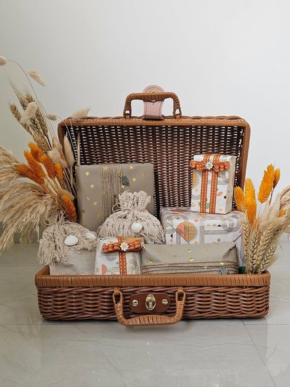 This hamper is a blend of warmth and happiness. I used a wicker picnic trunk and filled it with gifts wrapped in earthy, boho-inspired papers, accented with macrame potlis and dried flowers.