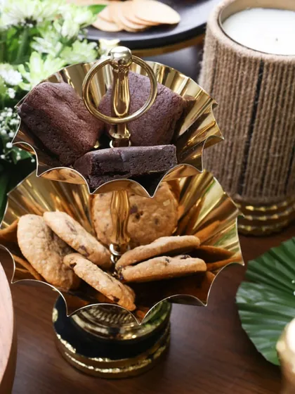 This two-tiered gold stand with scalloped edges is designed for serving sweets like brownies and cookies. Its polished finish and classic design bring a touch of timeless luxury to your high tea or dessert table.