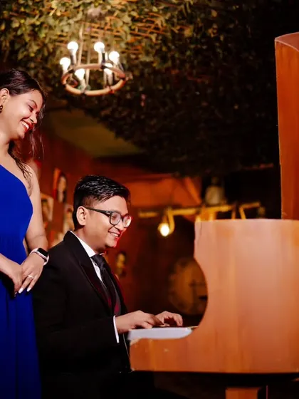A melody for his love. This intimate shot captures the groom playing the piano for his bride-to-be, creating a romantic and musical pre-wedding memory.