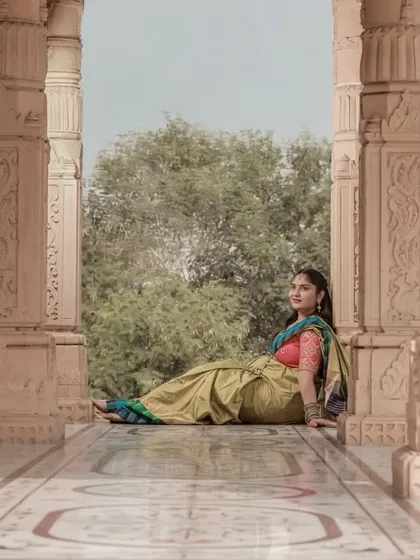 A low-angle shot capturing the grandeur of the location and the elegance of the mom-to-be in her saree.