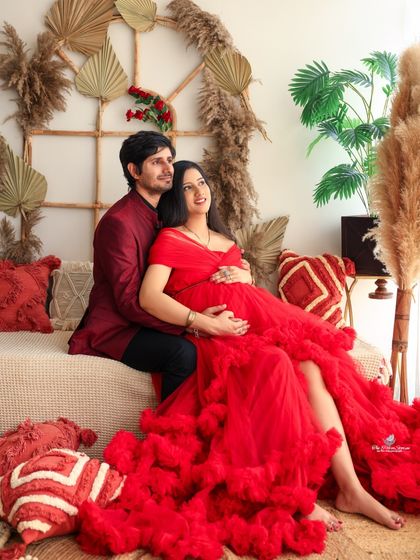 A comfortable and loving pose on the couch in our boho setup. The rich red of the gown contrasts beautifully with the neutral, earthy tones of the decor.
