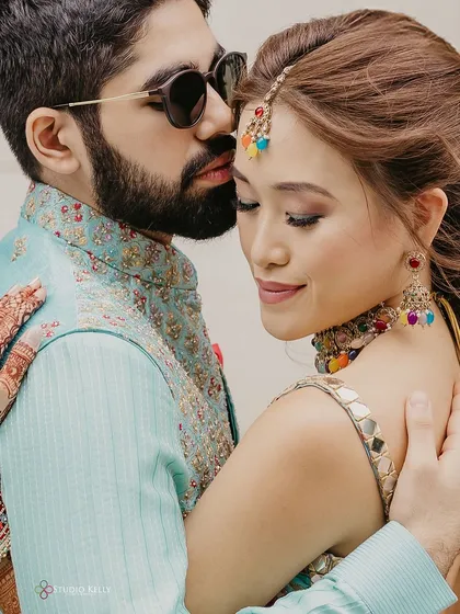 An intimate close-up of the couple during their Mehendi, capturing a tender moment and the bride's colorful jewelry.