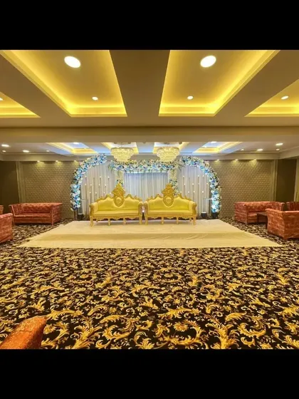 The stage and seating at Palm Beach banquet, available with a special discount. The patterned carpet and golden sofas add to the hall's charm.