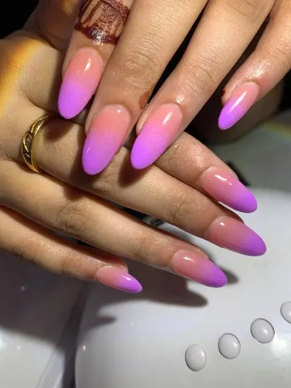 A beautiful pink and purple ombre design on long, almond-shaped nails.