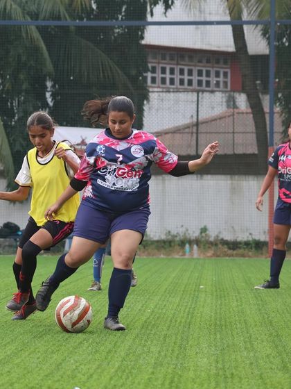 A player confidently carrying the ball forward, looking for a pass during a competitive league game.