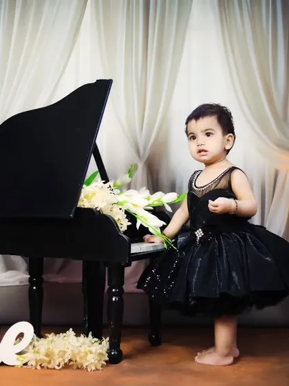 A full-length portrait of the birthday girl standing by the piano.
